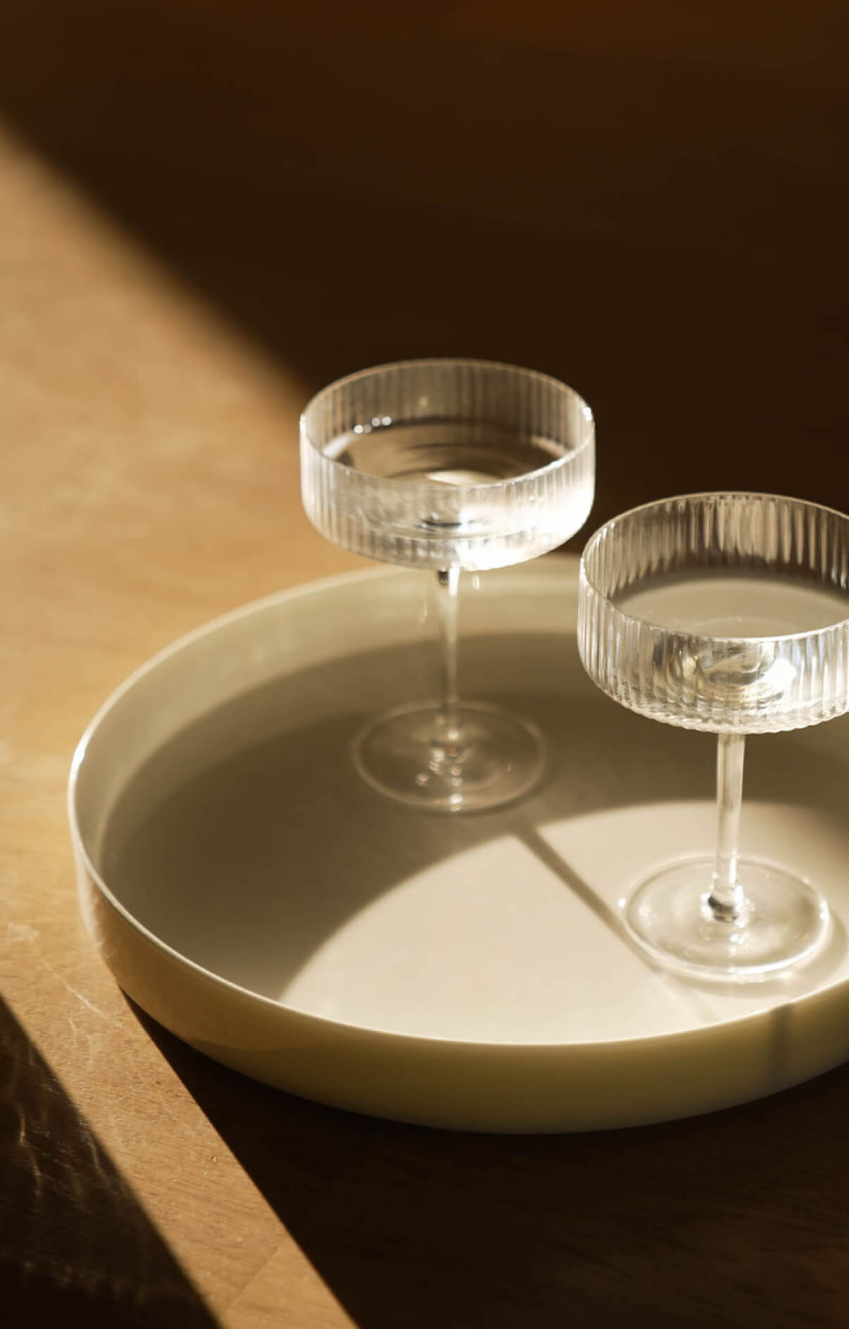 Close-up of two coupe glasses on a tray at The Code Austin with soft reflections and moody light.