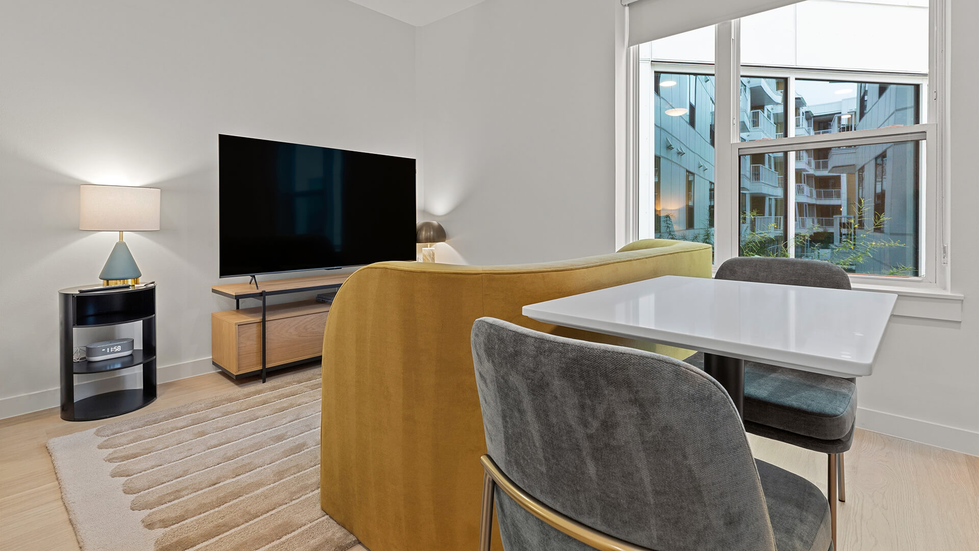 Studio at The Code Austin with a queen bed, Shady Grove palette kitchen, small sofa seating area, and two-seat dining table.