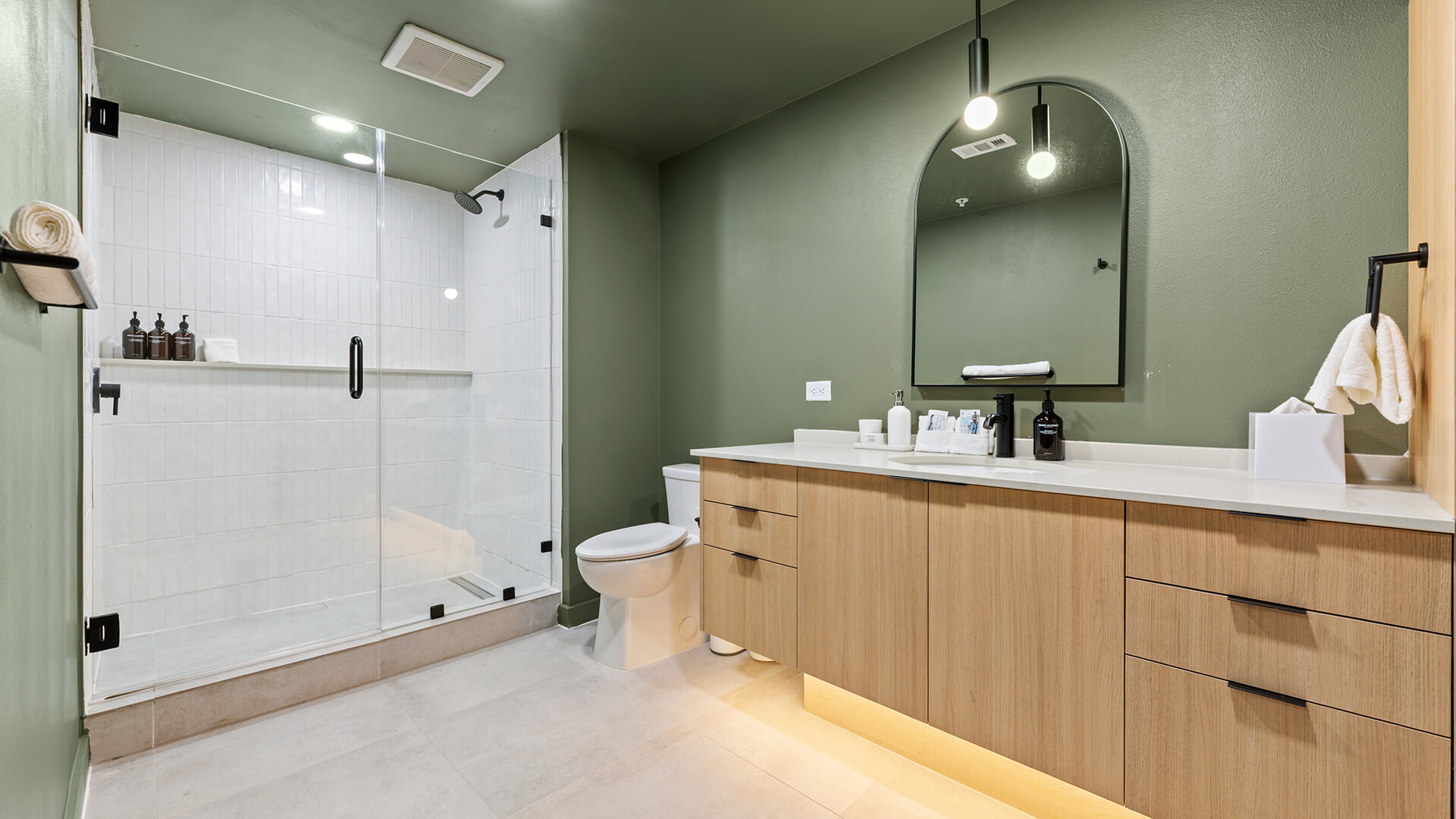 Interior design shot at The Code Austin inspired by South Congress style, featuring a moody retro-modern palette with soft neutrals, sage greens, warm earth tones, and tropical plants.