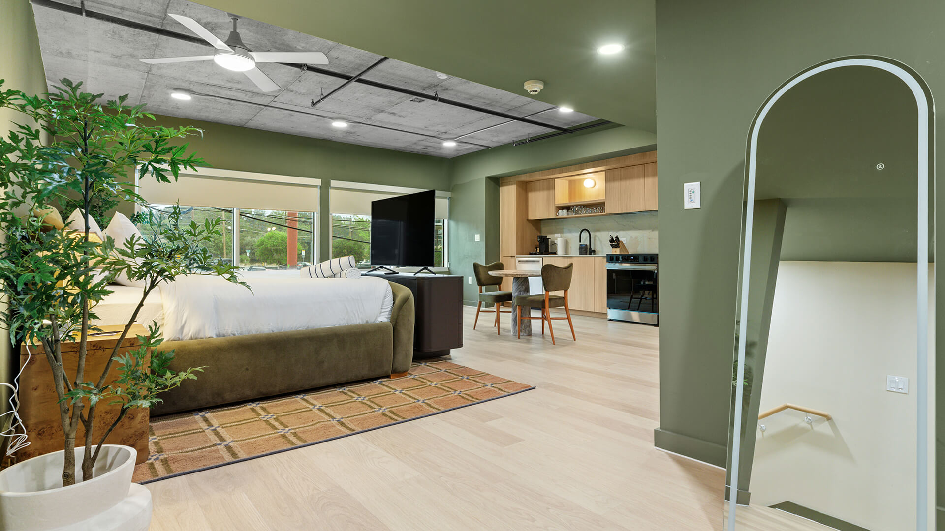 Interior design shot at The Code Austin inspired by South Congress style, featuring a moody retro-modern palette with soft neutrals, sage greens, warm earth tones, and tropical plants.